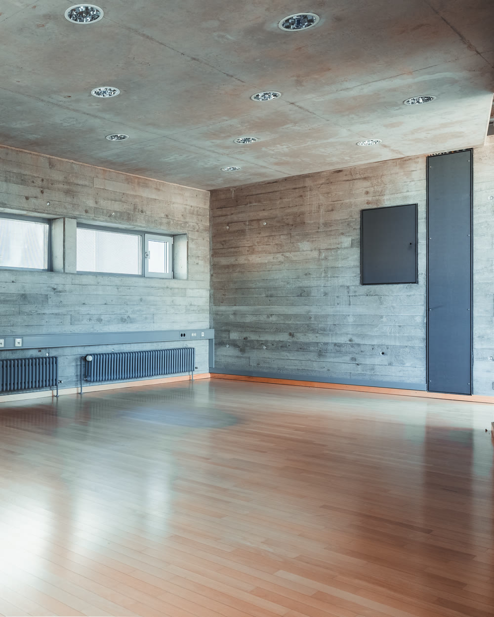 Büroraum mit Sichtbetonwänden, Holzfußboden und Tageslicht
