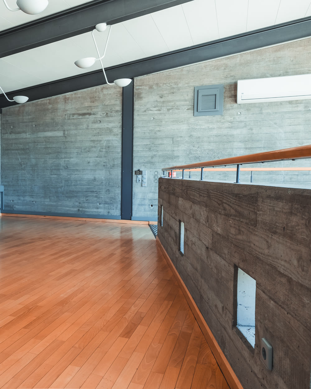 Bürobereich auf der Empore mit Glasgeländer und Sichtbeton